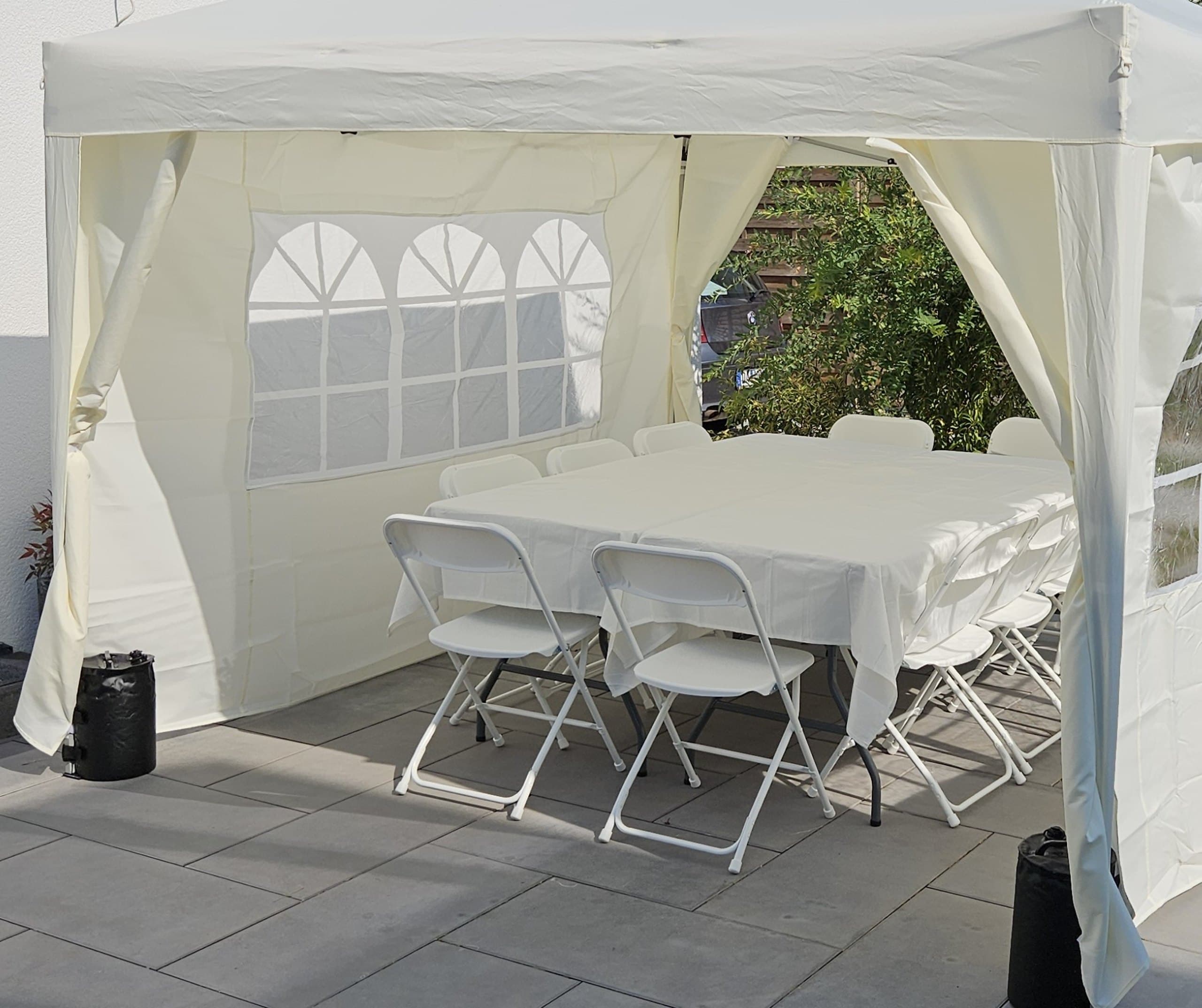 Partyzelt mit Tisch und Stühlen auf gepflasterter Terrasse